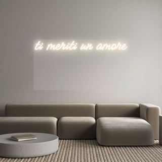 Personalized neon sign "ti meriti un amore" in warm white Meow Script font, backlit on plexiglass in a modern, cozy living room.