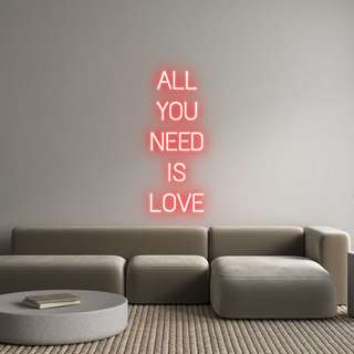 "Scritte neon personalizzate rosse con frase 'ALL YOU NEED IS LOVE' su parete sopra divano moderno"